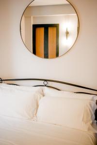 a mirror above a bed with white pillows at Sensole locanda contemporanea in Monte Isola