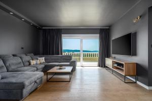 ein Wohnzimmer mit Couch und Flachbildfernseher in der Unterkunft Villa Marisa with 51sqm pool, 5 bedrooms, gym in Kaštela