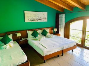 a bedroom with two beds with a green wall at Hotel Al Bosco in Sona