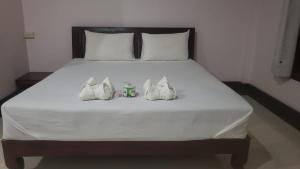a bed with white sheets and two bags on it at Mama Leurth Sunset Guesthouse in Don Det