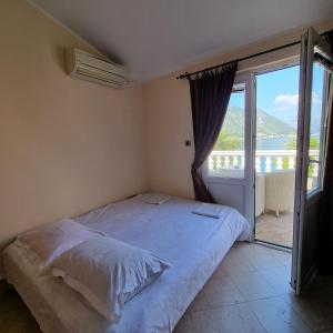 a bedroom with a bed and a large window at lovely apartment on the sea shore, with a view and free Wi-Fi in Kotor
