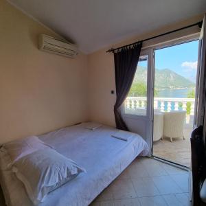a bedroom with a bed and a balcony with a view at lovely apartment on the sea shore, with a view and free Wi-Fi in Kotor
