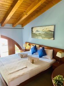 a bedroom with a large bed with blue pillows at Hotel Al Bosco in Sona
