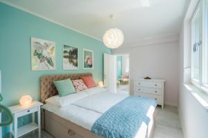 1 dormitorio con cama y pared azul en Harmony Boutique Villa, en Siófok