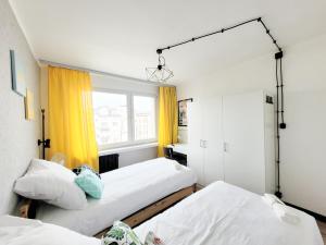 2 Betten in einem Zimmer mit gelben Vorhängen in der Unterkunft Pomorska Rooms in Łódź