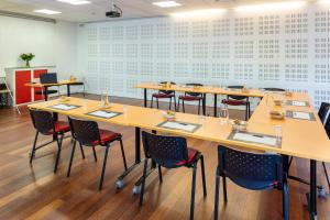 a conference room with tables and chairs in front of a wall at Le Trèfle in Portet-sur-Garonne