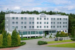Biały budynek z parkingiem przed nim w obiekcie Hotel Polski w Mielcu