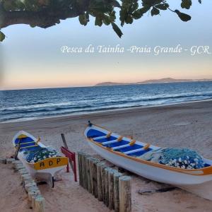 two boats sitting on a beach next to the ocean at CASA DA ANA E ZÉ in Governador Celso Ramos