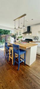 a kitchen with a wooden table and blue chairs at Stylish 3 Bedroom Townhouse in Brockley with Large Garden in London