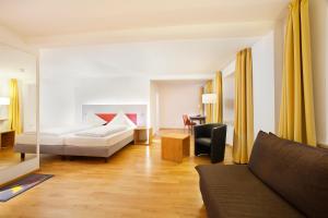 ein Wohnzimmer mit einem Bett und einem Sofa in der Unterkunft AKZENT Brauerei Hotel Hirsch in Ottobeuren