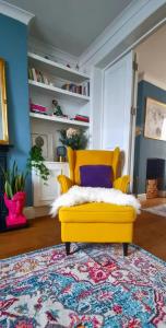 a yellow chair in a living room with a rug at Stylish 3 Bedroom Townhouse in Brockley with Large Garden in London