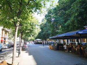 巴塞隆納的住宿－ApartEasy - Eixample Center，一条城市街道,人们坐在桌子和遮阳伞下