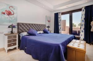 ein Schlafzimmer mit einem Bett mit einer blauen Decke und einem Fenster in der Unterkunft Exclusive frontline beach penthouse in Estepona + 23 Fotos