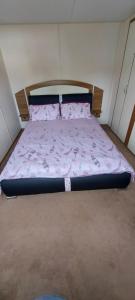 a bed in a small room with a pink comforter at Springs 46 by Vilija Southview Leisure Park Skegness in Skegness