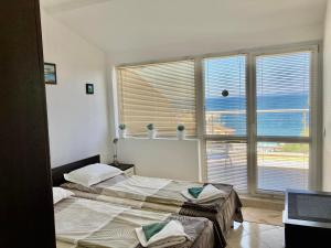 two beds in a room with two windows at Apolon Complex in Sozopol