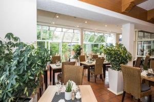a restaurant with tables and chairs and potted plants at AktiVital Hotel in Bad Griesbach
