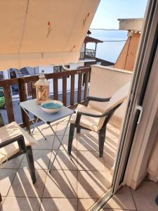 una mesa y sillas en un balcón con vistas al océano en Beautiful Seaside Studio, en Akráta