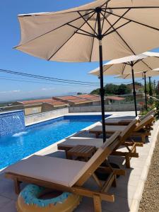 a pool with tables and umbrellas next to a swimming pool at Apartments Hillside in Ulcinj