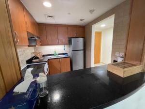 a kitchen with wooden cabinets and a black counter top at METRO Premium Location Spacious 2 Bedroom Apartment Right Next to the Metro in Dubai