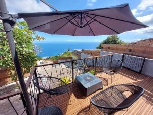 a balcony with a table and chairs and an umbrella at Bungalow tiayo in Saint-Leu