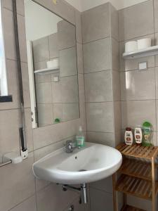 La salle de bains est pourvue d'un lavabo blanc et d'un miroir. dans l'établissement A Casa da Maria, à Horta