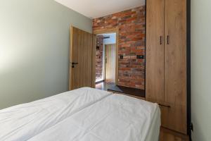 um quarto com uma cama e uma parede de tijolos em Bison Apartamenty em Bialystok