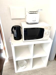 a microwave on a white shelf with a toaster at Garden house in Bolsena