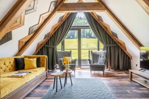 a living room with a yellow couch and two chairs at Apartamenty Polana pod Nosalem - zachód in Zakopane