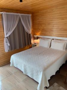 - une chambre avec un lit blanc et une fenêtre dans l'établissement Aconchego do Sereno Exclusive Chales, à Urubici