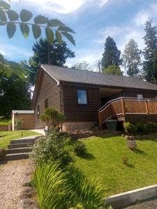 una casa de madera con terraza y césped en Charming lodge cosy comfortable ideal location en Blairgowrie