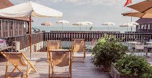 Hotel Mozart في رورشاخ: مجموعة من الكراسي والمظلات على سطح خشبي