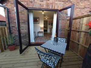 a patio with a table and chairs on a deck at Avocet Lodge, Snettisham in Kings Lynn
