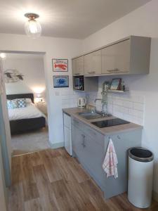 uma cozinha com um lavatório e uma cama num quarto em Avocet Lodge, Snettisham em King's Lynn