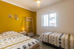 Cette chambre comprend 2 lits dans une chambre dotée de murs jaunes et d'une fenêtre. dans l'établissement Casa Almar by Portucasa, à Ferragudo