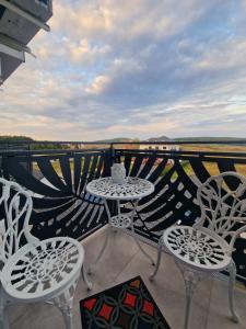 eine Terrasse mit 2 Tischen und Stühlen auf dem Balkon in der Unterkunft Blooming Apartment, Baile Felix in Baile Felix