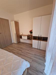 Blooming Apartment, Baile Felix في بايلي فيليكس: غرفة فارغة بها دواليب بيضاء وارضيات خشبية