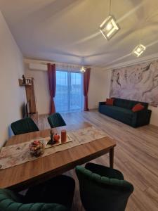 sala de estar con mesa de madera y sillas verdes en Blooming Apartment, Baile Felix, en Băile Felix