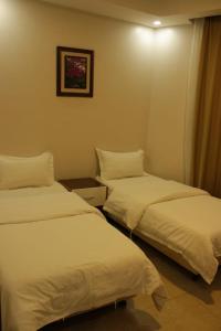 two beds in a hotel room with white sheets at شقق الفخامة للوحدات السكنية المفروشة in Al Madinah