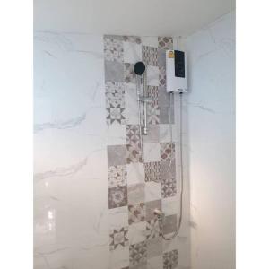 y baño con ducha y pared de azulejos. en Cha-am Beach Vacation Home en Cha Am