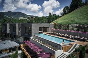 a building with a pool with chairs and a person in it at Sporthotel Wagrain in Wagrain