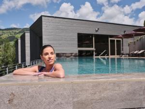 kobieta leżąca w basenie obok domu w obiekcie Sporthotel Wagrain w mieście Wagrain