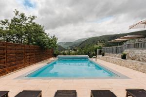 una piscina con una valla y montañas en el fondo en Hotel Restaurant du Fronton, en Itxassou