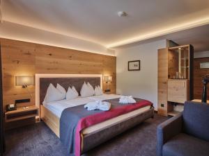 Pokój hotelowy z dużym łóżkiem i krzesłem w obiekcie Sporthotel Wagrain w mieście Wagrain +37 zdjęć