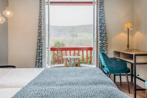 a bedroom with a bed and a desk and a window at Hotel Restaurant du Fronton in Itxassou