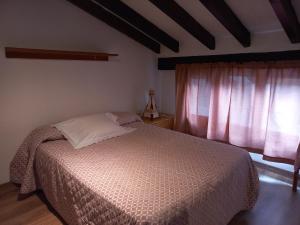 a bedroom with a bed and a window with pink curtains at La casuca del sol in Potes
