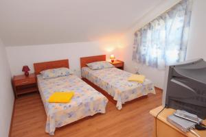 um quarto com duas camas e uma tv nele em Apartment Njivice 5458a em Njivice