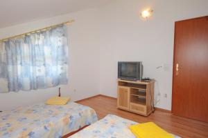 a bedroom with two beds and a tv on a dresser at Apartment Njivice 5458a in Njivice