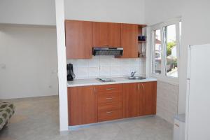 uma cozinha com armários de madeira e um lavatório em Apartment Njivice 5458a em Njivice