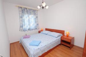 a bedroom with a bed with blue sheets and a window at Apartment Njivice 5458c in Njivice