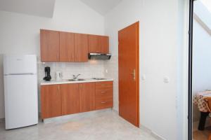 a kitchen with wooden cabinets and a white refrigerator at Apartment Njivice 5458c in Njivice